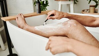 Man shaving his leg in bathroom